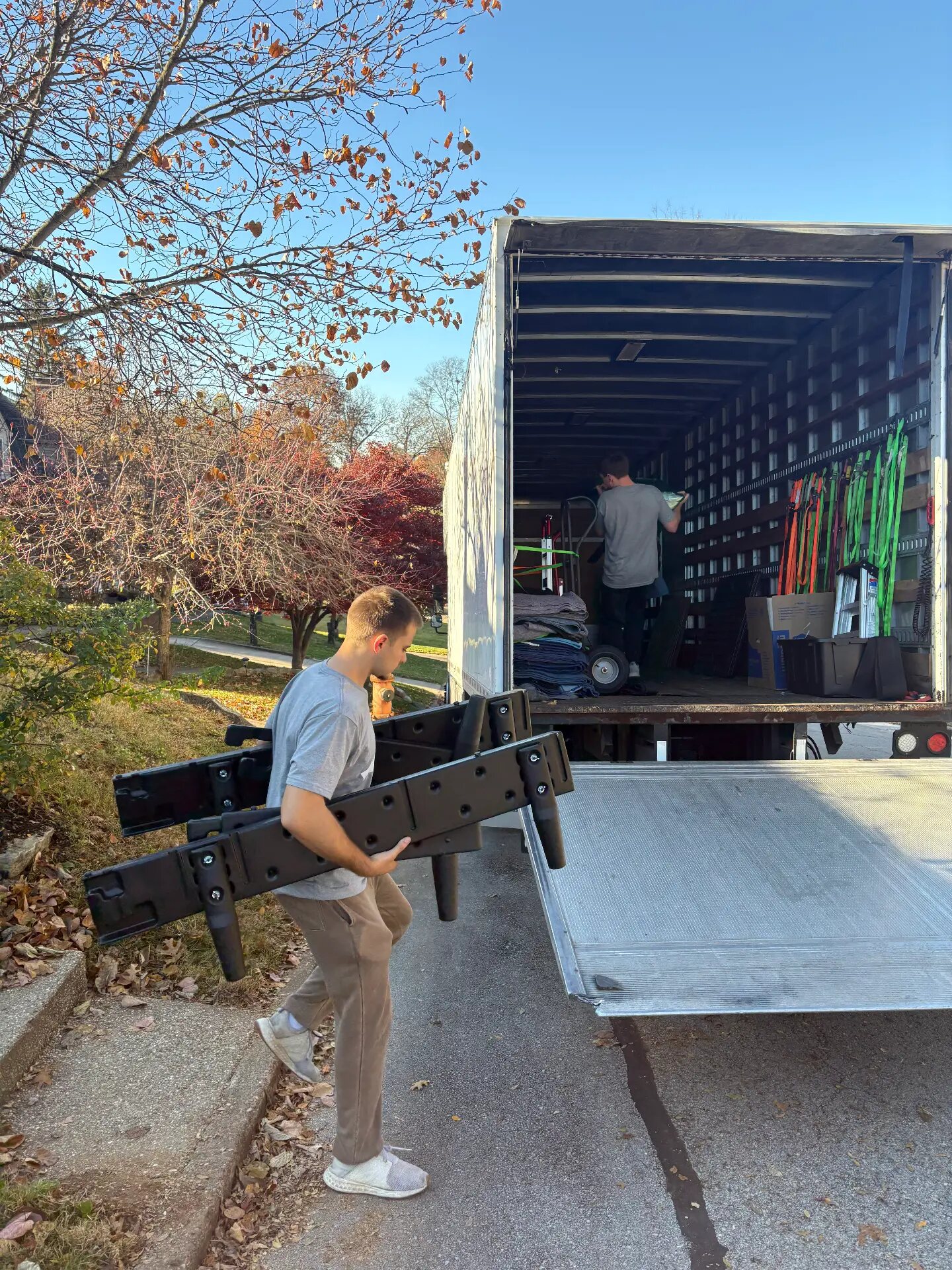 A D1 Moving & Logistics mover carrying disassembled furniture to the truck ramp outside a home